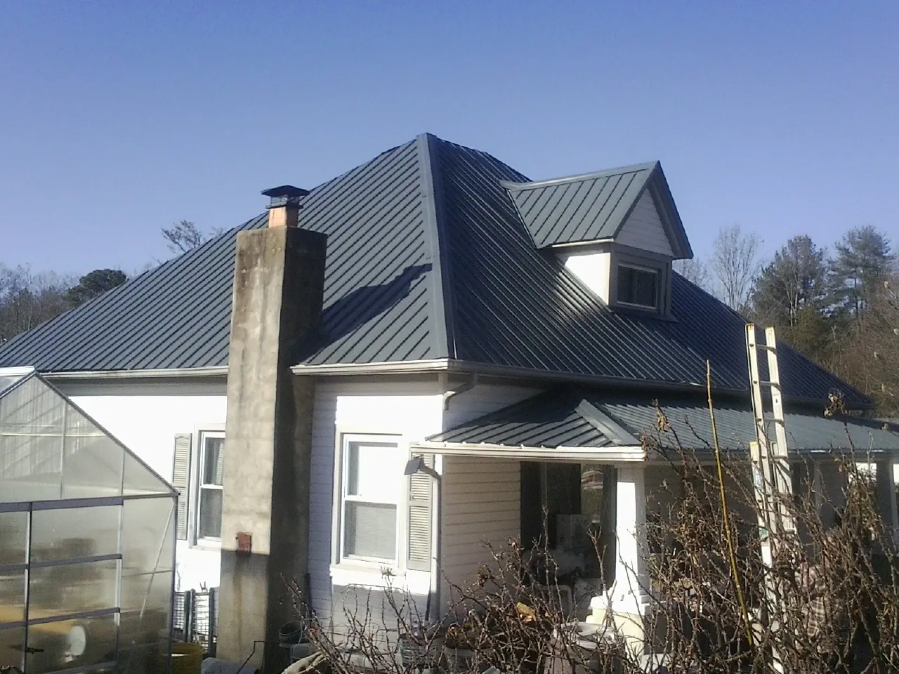 Dark blue standing seam metal roof on a white farmhouse with dormer — Slate & Tile Roof Repair by Roofing Brothers in Herriman