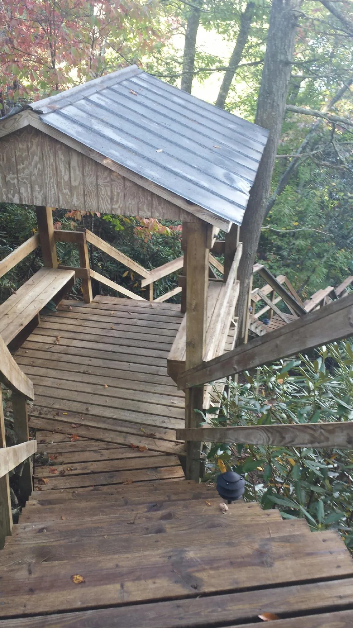 Metal roofed shelter over wooden steps on a wooded walkway — Skylight Repair & Installation work by our crew in Herriman