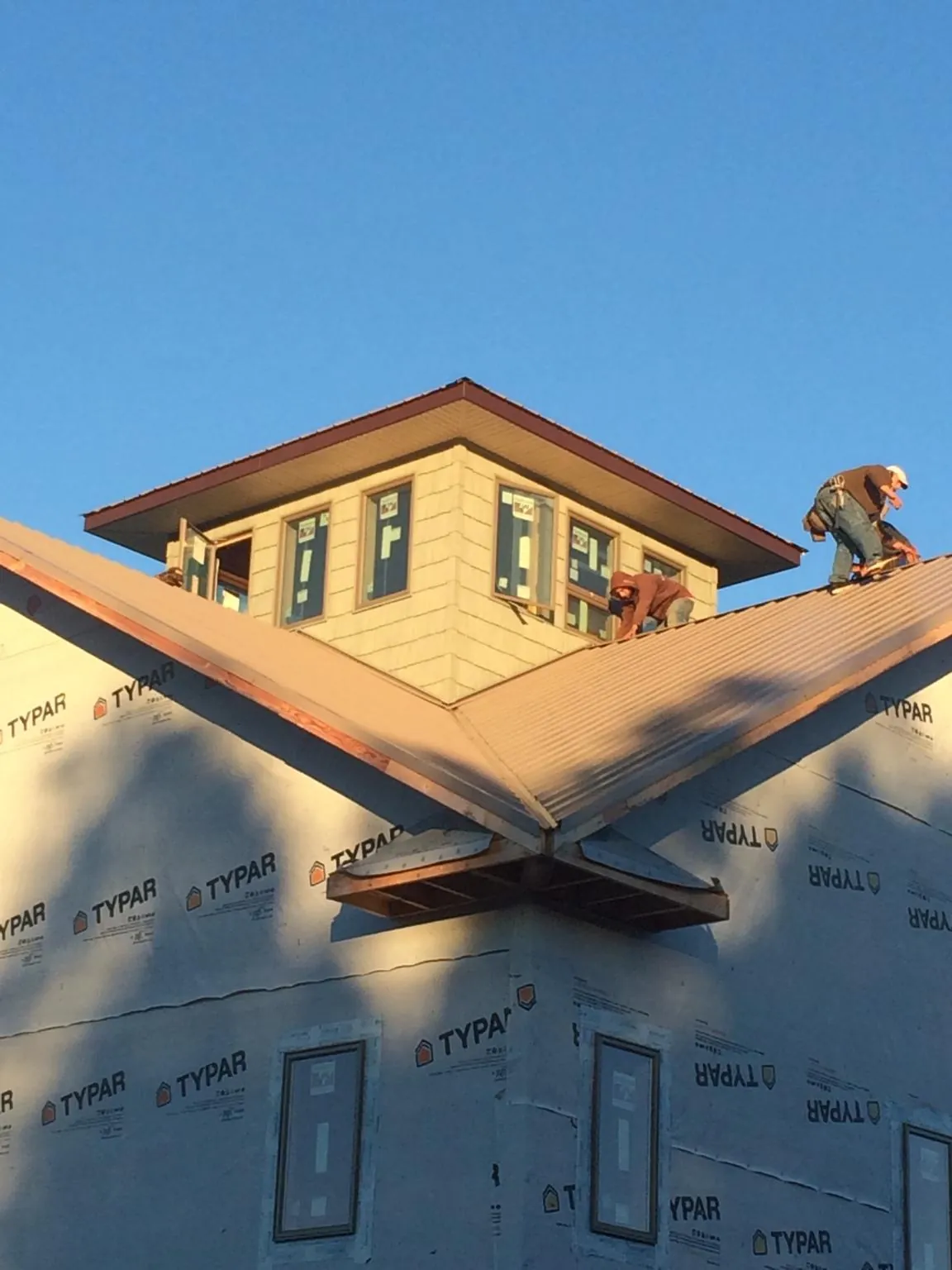 Roofers working around a rooftop cupola on a new metal roof at sunset — Roof Waterproofing in Herriman by Roofing Brothers
